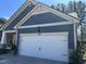 A well-kept two car garage with white carriage door in a home with gray siding and white trim at 12409 Angel Vale Pl, Durham, NC 27703