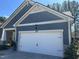 Attached two-car garage with white door, blue siding and tasteful landscaping at 12409 Angel Vale Pl, Durham, NC 27703