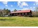 A beautiful single story house features a red metal roof, dark siding, and large grassy yard at 1796 Steel Bridge Rd, Sanford, NC 27330