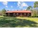 A charming single story home boasts a red metal roof, red shutters, and lush green lawn at 1796 Steel Bridge Rd, Sanford, NC 27330
