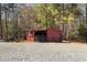 Exterior view of a red shed in a wooded backyard, offering extra storage or workspace at 1796 Steel Bridge Rd, Sanford, NC 27330