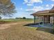 Cozy back porch with brick siding and views of the expansive, verdant lawn and agricultural field at 2125 W Academy St, Holly Springs, NC 27540