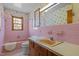 Pink bathroom with matching pink tile, sink, tub and toilet and floral wallpaper at 2125 W Academy St, Holly Springs, NC 27540