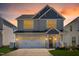 Charming two-story home featuring a two-car garage, and a welcoming front porch with a rocking chair at sunset at 2177 Campbell, Burlington, NC 27215