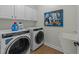 Laundry room with front-load washer and dryer, cabinetry and a sink, enhanced with a vibrant painting at 2310 Gilman St, Durham, NC 27703