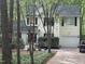 Charming two-story home with yellow siding, black shutters, and a red front door, nestled among mature trees at 27 Creeks Edge Ct, Durham, NC 27713