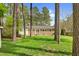 Scenic backyard view with lush lawn, towering trees, and a charming brick house at 3910 Hillgrand Dr, Durham, NC 27705