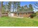 Expansive backyard features a brick house, patio, green grass, and a line of mature trees at 3910 Hillgrand Dr, Durham, NC 27705