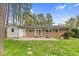 Spacious backyard with brick house, patio, lawn, and mature trees at 3910 Hillgrand Dr, Durham, NC 27705