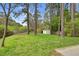 Lush backyard with tall trees, green lawn, wooden fence, and storage shed providing a serene outdoor space at 3910 Hillgrand Dr, Durham, NC 27705