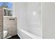 Clean bathroom includes tub with shower and built-in shelf, toilet, and window at 3910 Hillgrand Dr, Durham, NC 27705