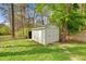 Close-up of a white storage shed in the backyard with grass and trees at 3910 Hillgrand Dr, Durham, NC 27705
