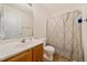 Bright bathroom featuring a vanity with updated hardware, a toilet, and a shower with patterned curtain at 4070 Landover Ln, Raleigh, NC 27616