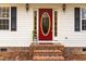 Inviting red front door with glass oval, flanked by side windows and black shutters, creating a warm welcome at 4324 Old Lewis Farm Rd, Raleigh, NC 27604