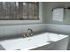 Close up of modern soaking tub with bronze fixtures next to a bright window at 4721 Cypress Ford Dr, Fuquay Varina, NC 27526