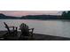 Tranquil waterfront scene with two Adirondack chairs on a wooden dock at sunset at 4721 Cypress Ford Dr, Fuquay Varina, NC 27526