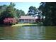Picturesque waterfront home with a beautiful wraparound porch, surrounded by colorful landscaping and mature trees at 4721 Cypress Ford Dr, Fuquay Varina, NC 27526