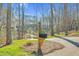 Mailbox view showing a glimpse of a home up a hill, surrounded by mature trees and lush greenery providing privacy at 4721 Cypress Ford Dr, Fuquay Varina, NC 27526