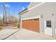 View of a multi-windowed wood garage door and white door with green landscaping providing privacy at 4721 Cypress Ford Dr, Fuquay Varina, NC 27526