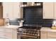 Bright kitchen features stainless steel stove, custom cabinetry, white counters, and dark backsplash at 4721 Cypress Ford Dr, Fuquay Varina, NC 27526