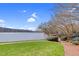 Beautiful lake view featuring a lush lawn, a brick walkway, and serene waters under a blue sky at 4721 Cypress Ford Dr, Fuquay Varina, NC 27526