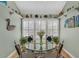 Bright breakfast nook with a round glass table set below decorative open shelving and shuttered windows at 515 Swim & Croquet, Pittsboro, NC 27312