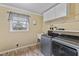 Modern laundry room with front loading washer and dryer, storage cabinets, utility sink and window at 7155 Old Fairground Rd, Benson, NC 27504