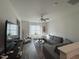 Bright living room features a large grey couch, ceiling fan and a large window providing ample natural light at 829 S Franklin St, Wake Forest, NC 27587
