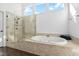 Bright bathroom featuring a soaking tub with tiled surround, glass enclosed shower, and transom windows at 101 Listokin Ct, Cary, NC 27519