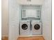 Functional laundry room featuring side-by-side washer and dryer, cabinets for supplies, and hardwood floors at 102 Battenburg Ct, Cary, NC 27519