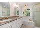 Bright main bathroom featuring dual sinks, granite countertops, a jacuzzi tub, and a glass shower at 102 Battenburg Ct, Cary, NC 27519