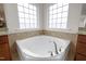 Bright bathroom features a large soaking tub beneath two gridded windows offering natural light at 105 Concordia Woods Dr, Morrisville, NC 27560