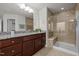 Beautiful bathroom with a glass shower, granite counters, dark cabinetry and a large mirror at 105 Concordia Woods Dr, Morrisville, NC 27560