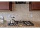 Detailed view of stovetop with granite countertops, stainless steel stovetop, and tile backsplash at 105 Concordia Woods Dr, Morrisville, NC 27560