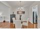 Elegant dining room with a glass-top table, white chairs, and modern light fixture at 10707 Edmundson Ave, Raleigh, NC 27614