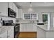 A bright kitchen with stainless steel appliances, granite countertops, white cabinets, and a hardwood floor at 10707 Edmundson Ave, Raleigh, NC 27614