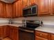 Well-lit kitchen featuring wooden cabinetry, modern black appliances, and light countertops at 11619 John Allen Road Rd, Raleigh, NC 27614