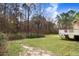 Lush backyard with scattered leaves, bordered by trees, and featuring a partial view of the deck at 129 Bennett Pl, Clayton, NC 27527