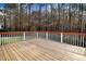 View of a wooden deck with a white railing overlooking a lush, wooded backyard at 129 Bennett Pl, Clayton, NC 27527