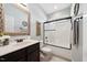 Bathroom features dark cabinets, a tub with a glass door, and a white countertop at 153 Brindley Cir, Clayton, NC 27520