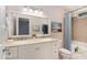 Bright bathroom features a double sink vanity, framed mirrors, tub with shower, and neutral tile at 1603 Stonegate S, Sanford, NC 27332
