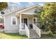 Charming home featuring light gray siding, white trim, and a welcoming front porch with steps and chair at 1614 Homewood Ave, Durham, NC 27707