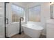 A standalone tub next to two windows offers a relaxing space to soak in this sleek bathroom design at 244 Victor Ct, Garner, NC 27529