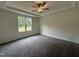 Bright primary bedroom with a tray ceiling, plush carpeting, and a large window overlooking the yard at 274 Longbow Dr, Middlesex, NC 27557