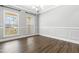 Bright dining room with hardwood floors, wainscoting, and a chandelier, illuminated by natural light from two large windows at 3574 Johnson Grant Dr, New Hill, NC 27562