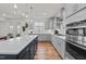 Open kitchen with stainless steel appliances, large island, hardwood floors, and modern pendant lighting at 505 Marion Hills Way, Knightdale, NC 27545
