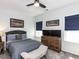 Cozy bedroom with a ceiling fan, dresser with mounted TVs, and lovely natural light at 521 Ivy Arbor Way, Holly Springs, NC 27540