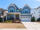 Charming two-story home with blue siding, a well-manicured lawn, and an attached two-car garage at 521 Ivy Arbor Way, Holly Springs, NC 27540