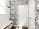 Stylish mudroom featuring decorative wallpaper, a white bench with storage, and access to additional rooms at 521 Ivy Arbor Way, Holly Springs, NC 27540