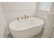 Modern soaking tub with stylish fixtures, surrounded by white wainscoting and natural light at 56 Mist Wood Ct, Pittsboro, NC 27312